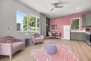 Un apartamento moderno con sala de estar, comedor y cocina. Cuenta con ventilador de techo, ventanas amplias y vista al exterior.