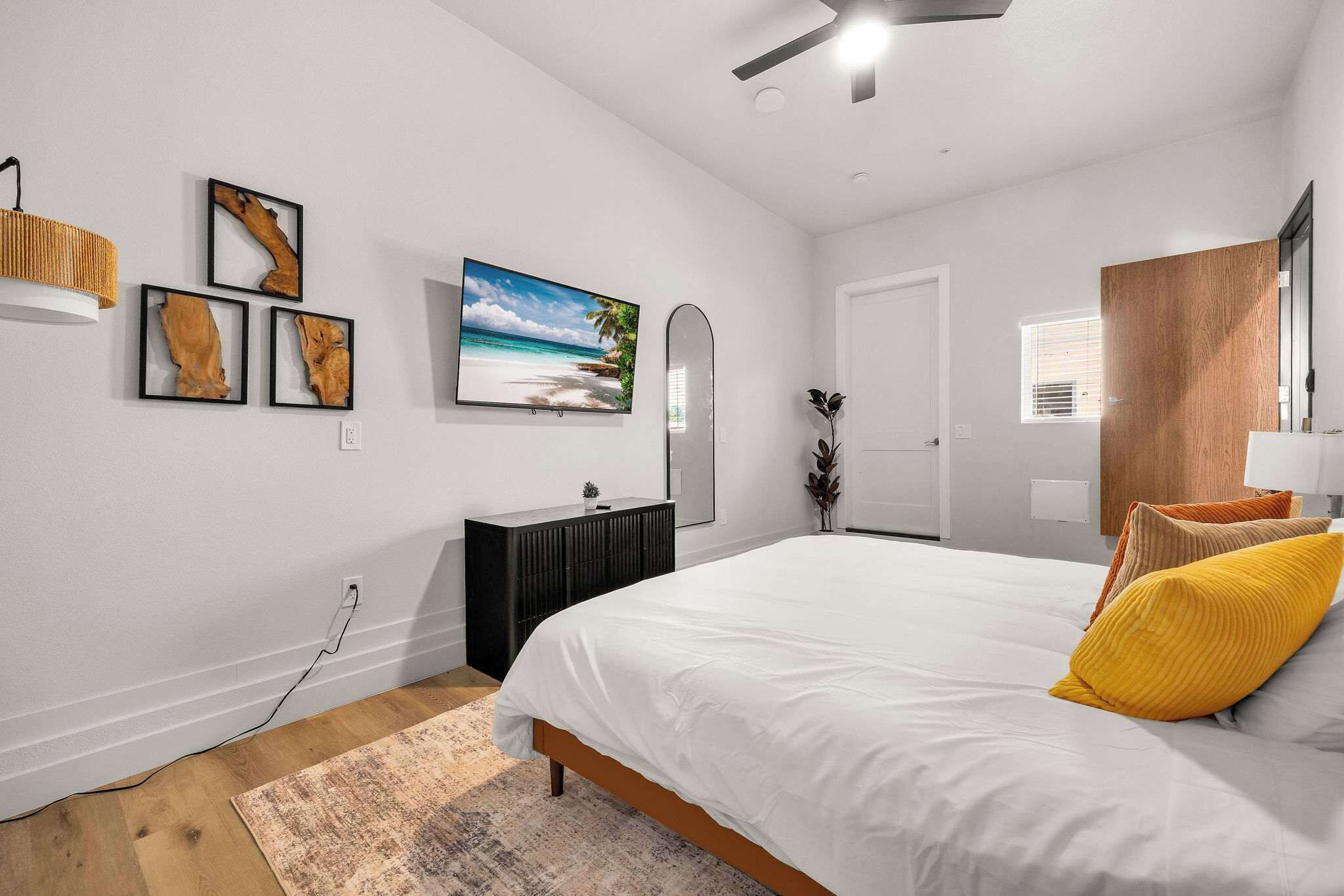 A bedroom with a bed, a dresser, a mirror, and wall art.