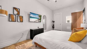 Un dormitorio con cama, cómoda, espejo y decoración en la pared.