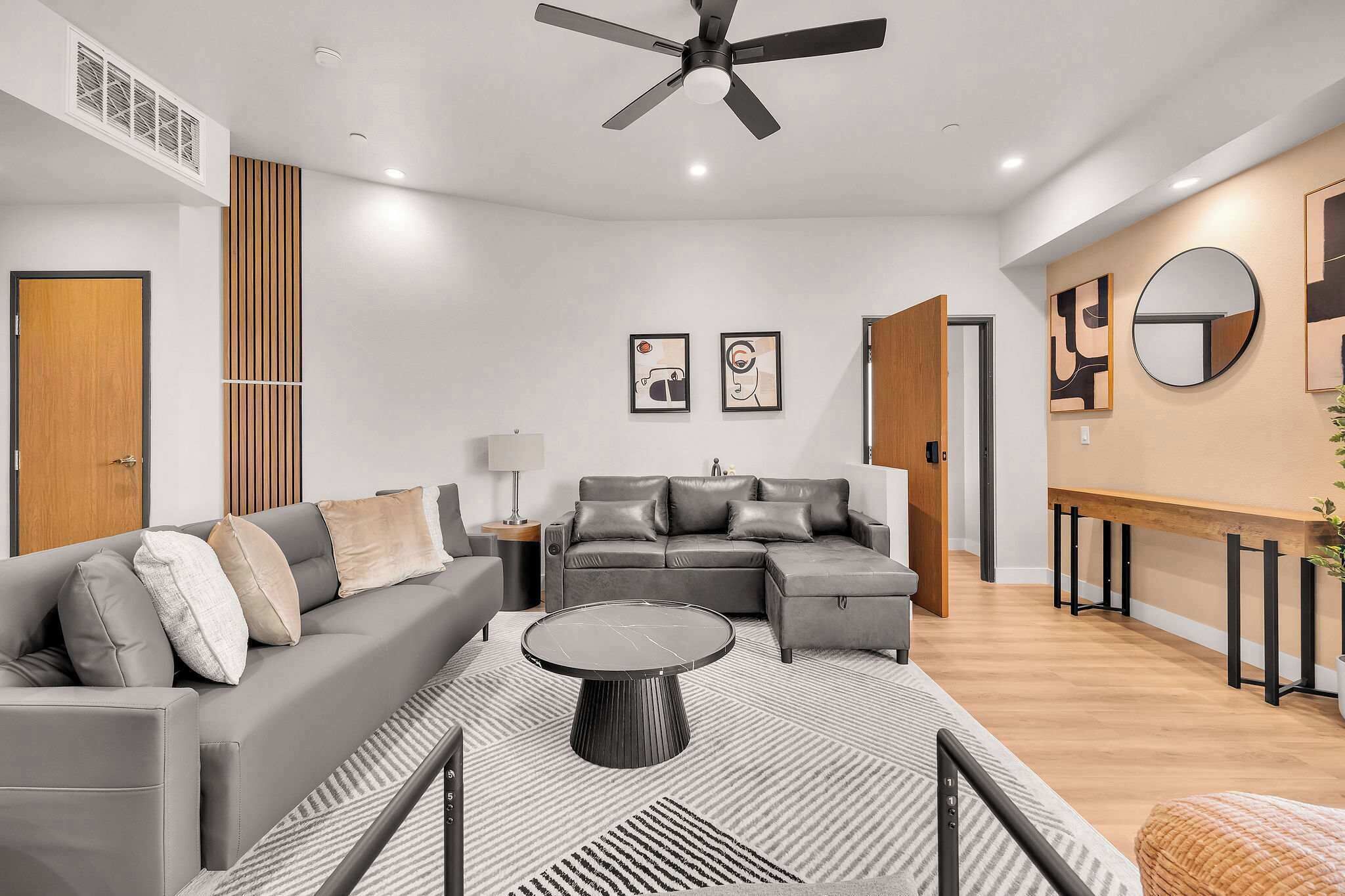 Ein modernes Wohnzimmer mit einem Ecksofa, einem Couchtisch und einem Deckenventilator.