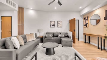 Ein modernes Wohnzimmer mit einem Ecksofa, einem Couchtisch und einem Deckenventilator.