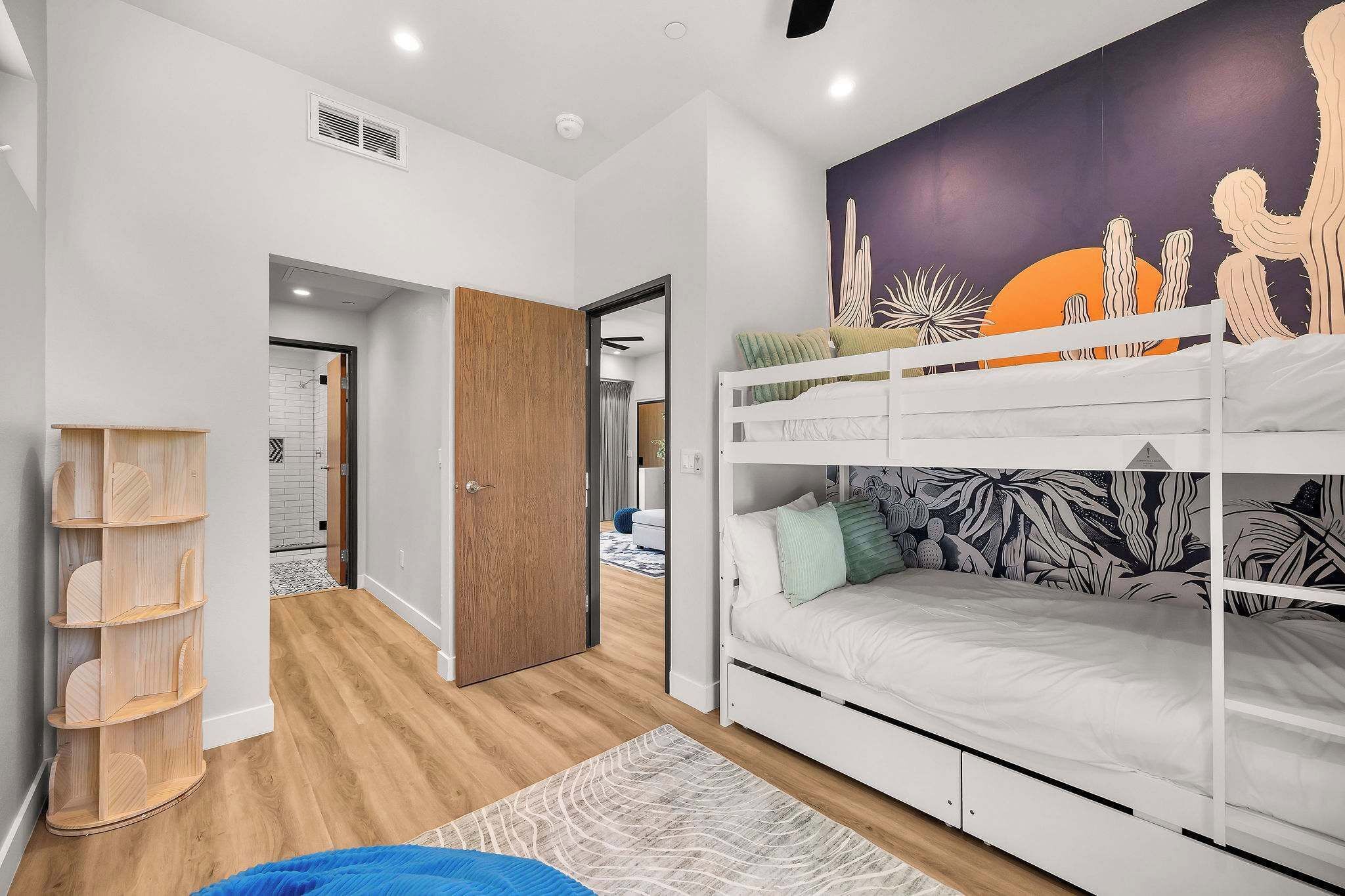 A room with a bunk bed, a wooden shelf unit, and a wall mural.