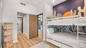 A room with a bunk bed, a wooden shelf unit, and a wall mural.