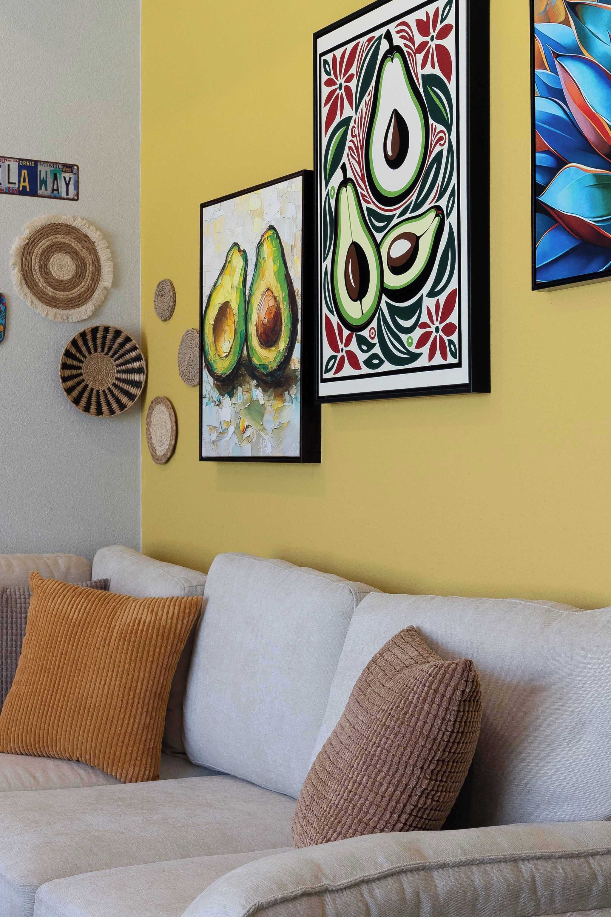 A living room with a yellow wall, a beige sofa, and two framed avocado paintings.
