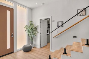 Un interior moderno con una escalera de madera, una planta en maceta y un diseño minimalista.