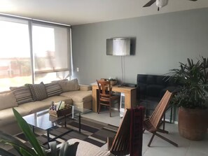 A living room with a sofa, coffee table, TV, and a large window. - Departamento de Lujo Exclusivo, Vista y Literas. (tlajomulco de zuñiga)