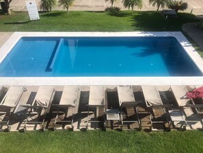 Ein rechteckiger Swimmingpool mit glatter, blauer Wasseroberfläche, umgeben von einer weißen Umrandung.
