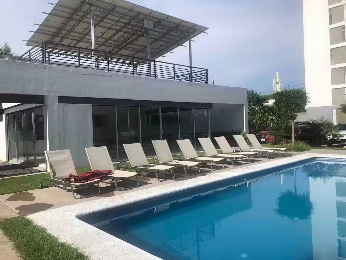 Une piscine avec des chaises longues et un espace abrité.
