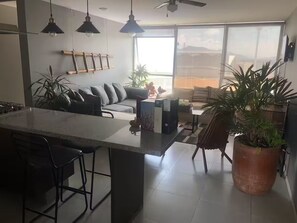 Eine moderne Küche mit einer zentralen Kochinsel, Barhocker und einem Essbereich mit einer Couch und Tisch.