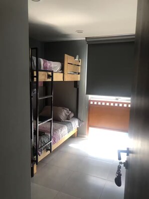 Een slaapzaal met stapelbedden, een raam en een deur.