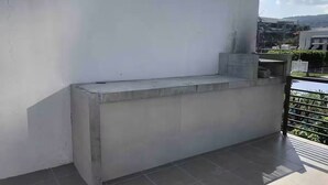 A concrete bench on a tiled balcony with a white wall and a metal railing. - Departamento de Lujo Exclusivo, Vista y Literas. (tlajomulco de zuñiga)