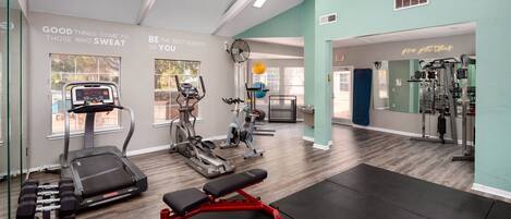 A gym with treadmills, elliptical machines, and free weights.