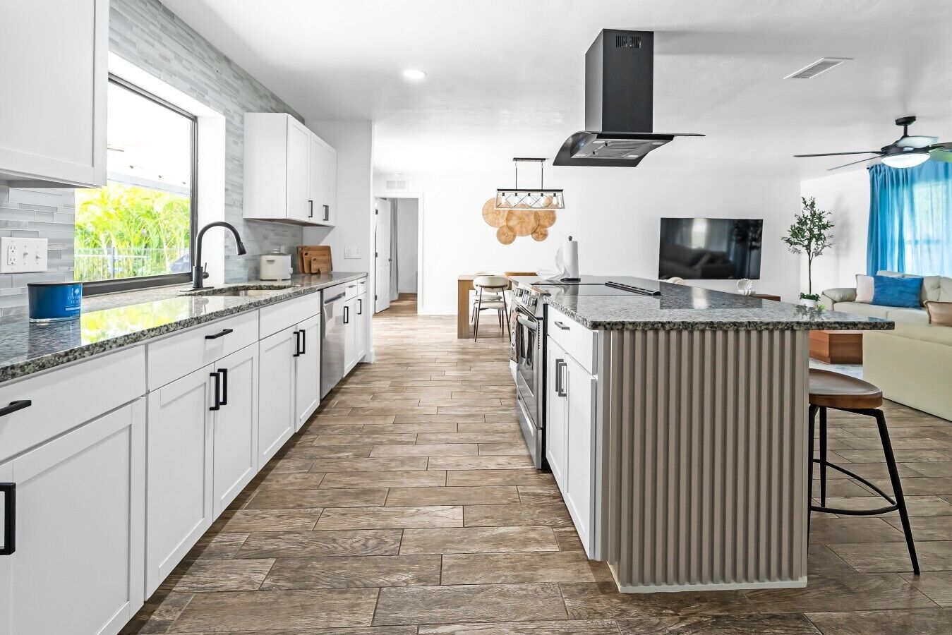 Una cocina moderna con armarios blancos, una isla grande y una estufa integrada.