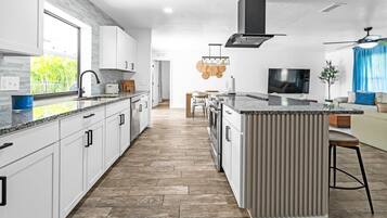 Una cocina moderna con armarios blancos, una isla grande y una estufa integrada.