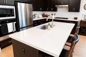 A modern kitchen with a stainless steel refrigerator, a built-in oven, a microwave, and a sink with a faucet. - Thoughtfully Designed Lodi Retreat - Fire Pit • Putting Green • Near Wineries (Lodi)