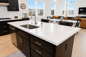 Eine moderne Küche mit einer großen Kochinsel, Edelstahlgeräten und einem Essbereich mit einer Couch und einem Tisch.