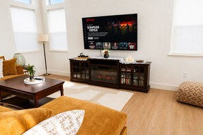 A living room with a fireplace, a television displaying a Netflix series, and a cozy seating area. -  Thoughtfully Designed Lodi Retreat - Fire Pit • Putting Green • Near Wineries (Lodi)