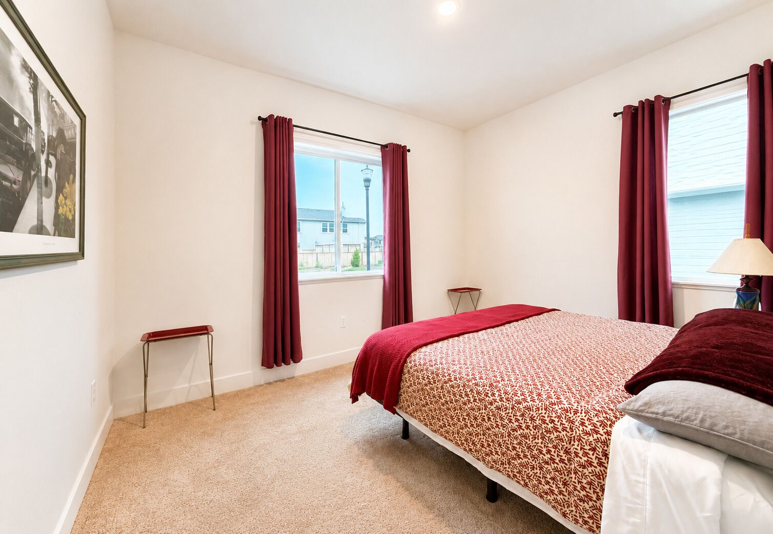 Une chambre à coucher avec un lit, une fenêtre avec des rideaux, une petite table et une lampe.