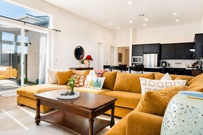 Ein stilvolles Wohnzimmer mit einer Couch, einem Couchtisch und einer Küchenzeile im Hintergrund.