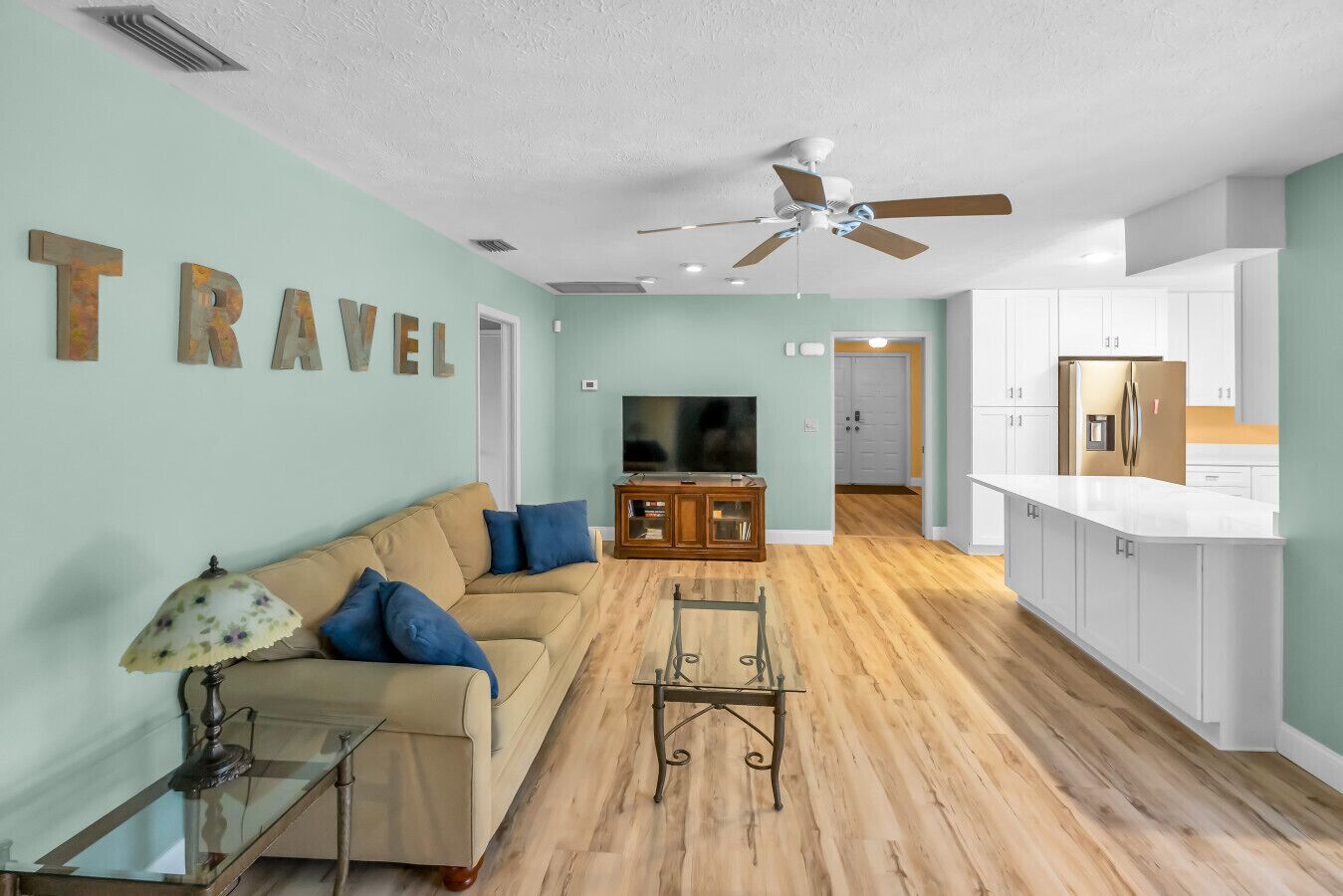 A living room with a sofa, TV, and a ceiling fan.
