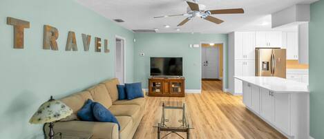 Una sala de estar con un sofá, televisor y ventilador de techo.