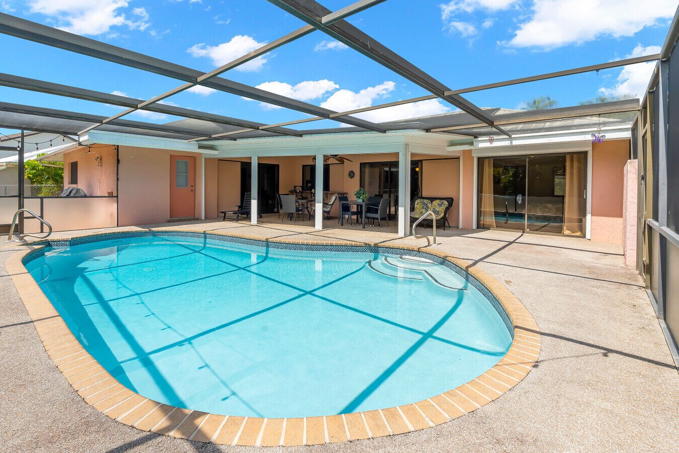 Ein überdachter Patio-Bereich, ein Innenpool und Blick auf die umliegenden Gebäude bei strahlend blauem Himmel.