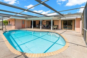 Ein überdachter Patio-Bereich, ein Innenpool und Blick auf die umliegenden Gebäude bei strahlend blauem Himmel.