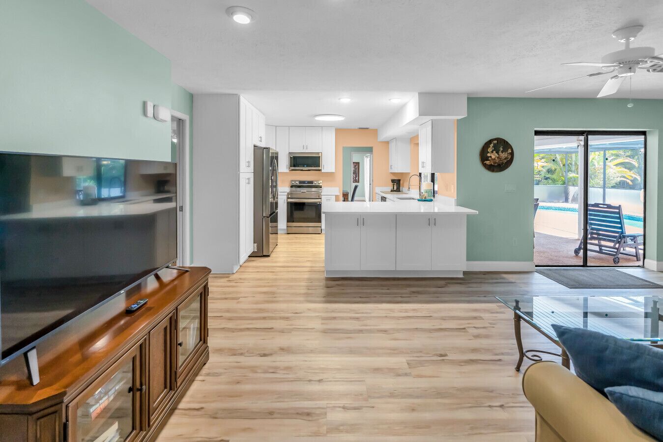 A modern kitchen with white cabinets, a central island, and a dining area with a glass table.