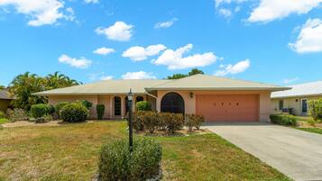 A single-story house with a garage, a well-maintained lawn, and a clear sky.