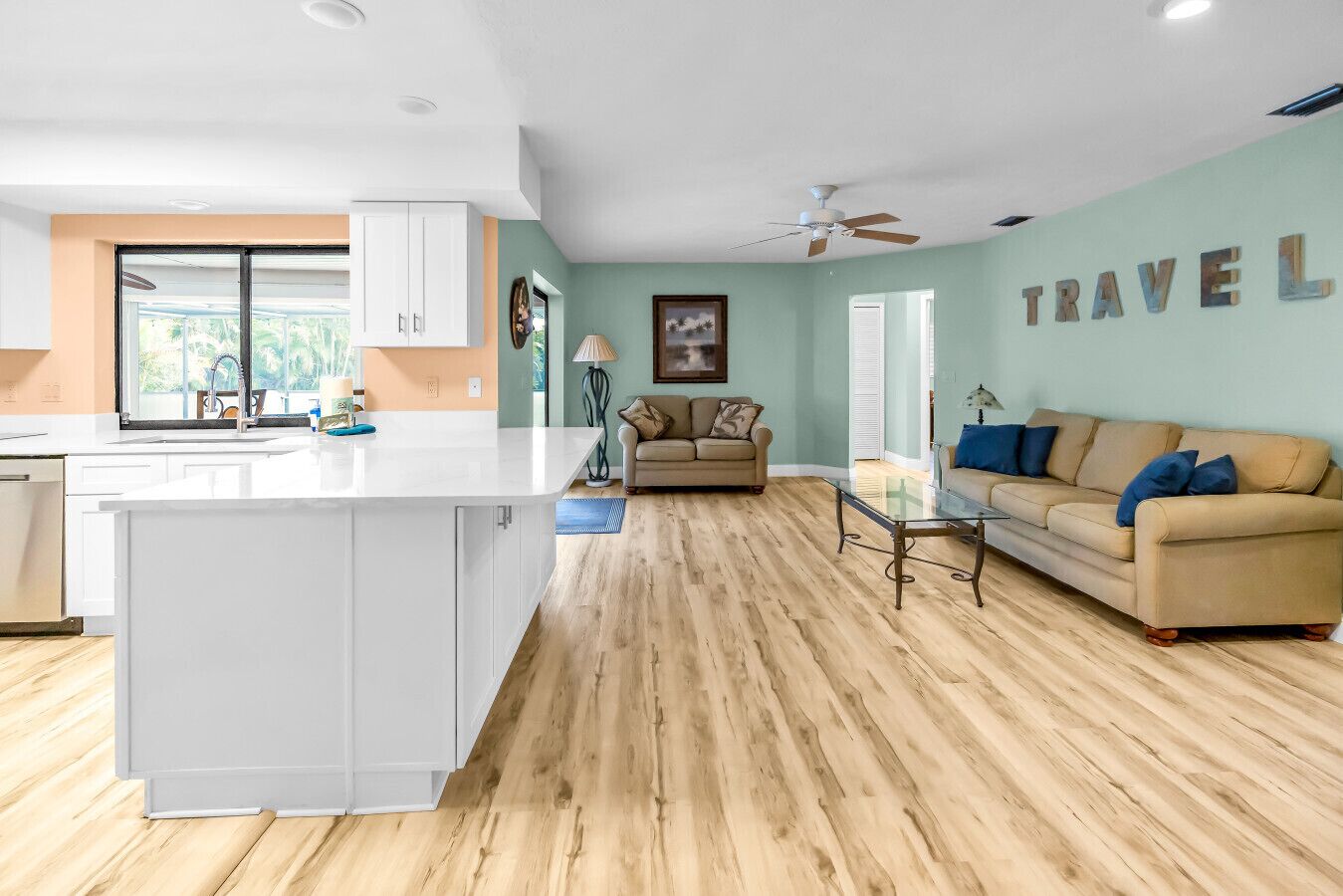 Een moderne keuken met witte kasten, een centraal eiland en een eetgedeelte met een glazen tafel.