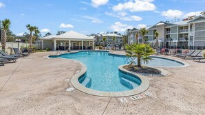 A pool area with lounge chairs and a covered seating area. - Sunnyside Village-3A condo near Marshwalk with pool (Murrells Inlet)