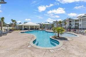 A pool area with lounge chairs and a covered seating area. - Sunnyside Village-3A condo near Marshwalk with pool (Murrells Inlet)