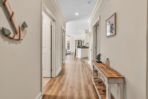 A hallway with wooden flooring, white walls, and a wooden bench with decorative items. - Sunnyside Village-3A condo near Marshwalk with pool (Murrells Inlet)