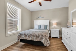 A bedroom with a bed, a nightstand, a dresser, a ceiling fan, and a window with blinds. - Sunnyside Village-3A condo near Marshwalk with pool (Murrells Inlet)