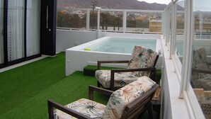 Una terrazza sul tetto con piscina, due poltrona relax e vista su una montagna.