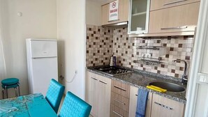 Cuina amb saló menjador, taula i cadires, i zona de cuina amb reixes de ceràmica, fogó i armaris.