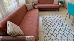 Un saló amb dos sofàs, una catifa estampada i un frigorífic blanc.