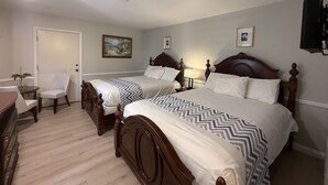 Una habitación de hotel con dos camas de madera, una silla, un escritorio y una puerta.