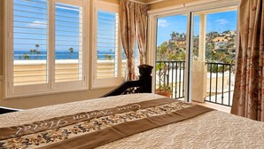 Un dormitorio con cama, vistas a la playa y un balcón con barandilla.