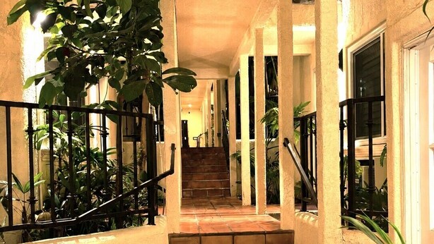 Un pasillo con piso de baldosas, una escalera y plantas en macetas.