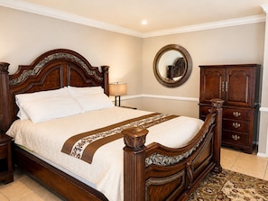 Un dormitorio con cama de madera, una mesita de noche, un aparador y un espejo en la pared.