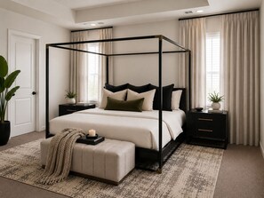 Ein Himmelbett mit neutraler Farbgestaltung, ein Nachttisch mit Pflanze und ein gemustertes Teppich.