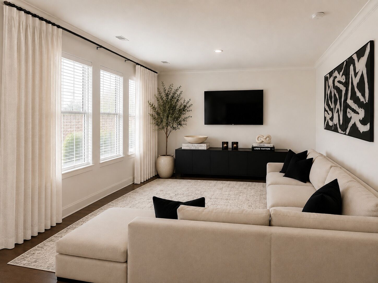 A living room with a beige sofa, a black entertainment unit, and a large TV on the wall.