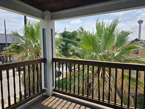 A balcony with a wooden railing, palm trees, and a view of a tower in the background. - Beautiful two minutes from Alamodome and all downtown fun (San Antonio)