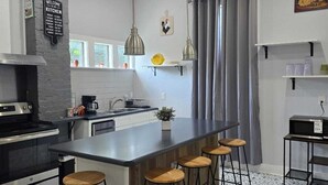 Een moderne keuken met een centraal eiland, barkrukken, hanglampen en een schoolbord.