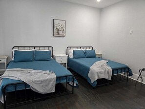Ein Zimmer mit zwei Einzelbetten, weißen Nachttischen und einem gerahmten Bild an der Wand.