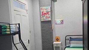 Een slaapkamer met stapelbedden, een plafondventilator, een wandlamp en een motiverende poster.