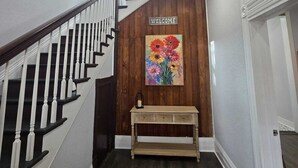 Een trap met een 'WELCOME' bord en een bloemschilderij erboven.
