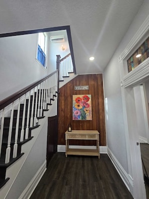 A staircase with a 'WELCOME' sign and a floral painting above it. - Beautiful two minutes from Alamodome and all downtown fun (San Antonio)