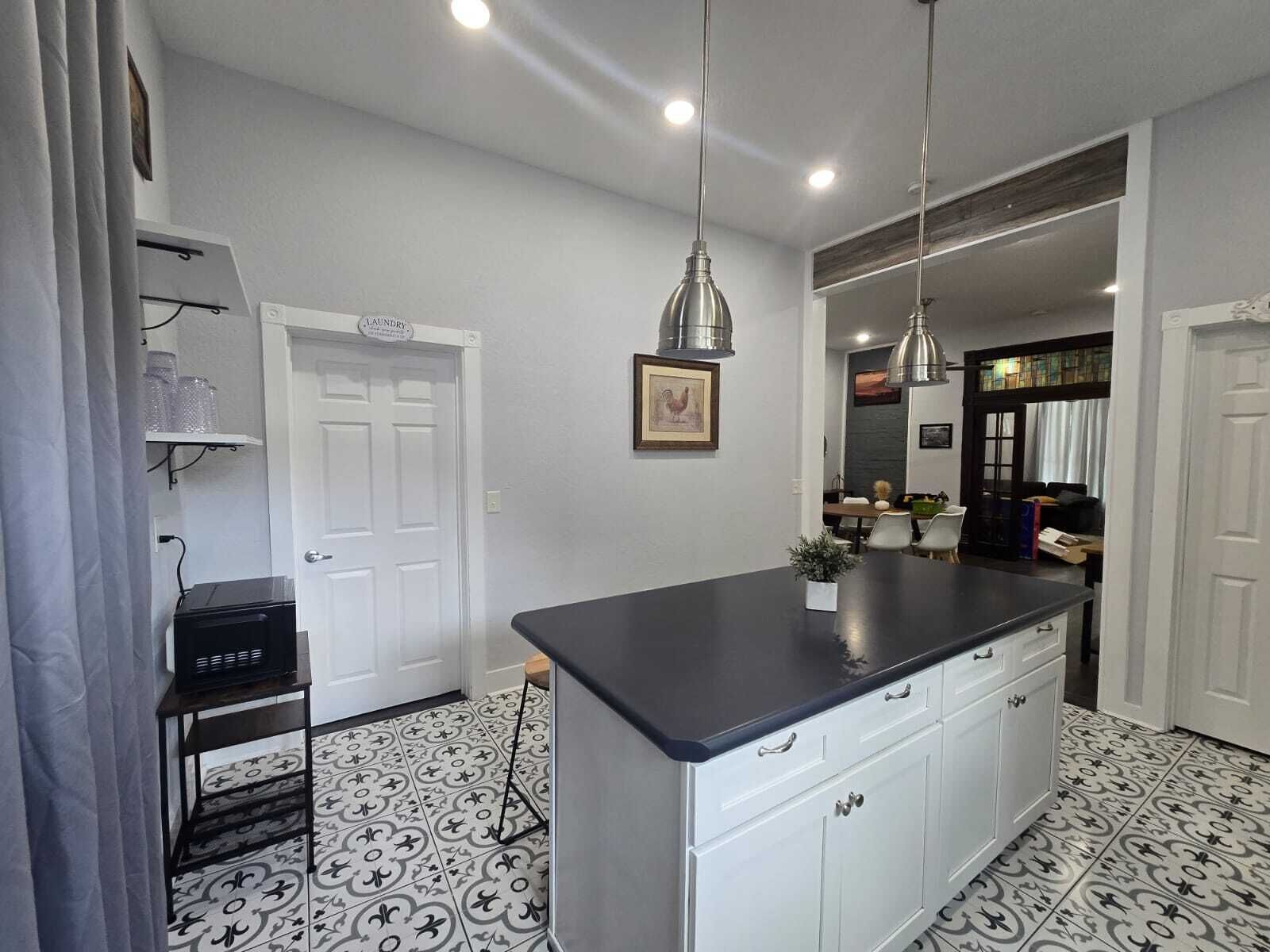 A kitchen with a central island, pendant lighting, and a patterned floor.